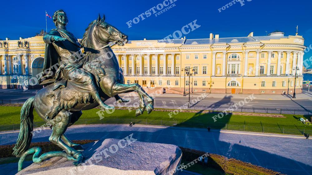 Величественный памятник Петру Первому — Медный всадник — на фоне утреннего Санкт-Петербурга и реки Невы во время рассвета. Первые лучи солнца освещают исторический центр северной столицы России, создавая атмосферный городской пейзаж с отражениями света в воде и знаменитым символом Петербурга. Фотография передаёт культурное наследие города, красоту архитектуры и романтичную атмосферу раннего утра на Неве. Изображение идеально подходит для публикаций о достопримечательностях Санкт-Петербурга, путешествиях по России, исторических памятниках, городской архитектуре и туристических маршрутах.